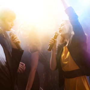 Party at night club. Group of friends singing and dancing