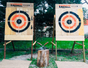 Cibles mobiles pour le lancer de haches du Karnage Club, derrière deux haches plantées dans un rondin en bois