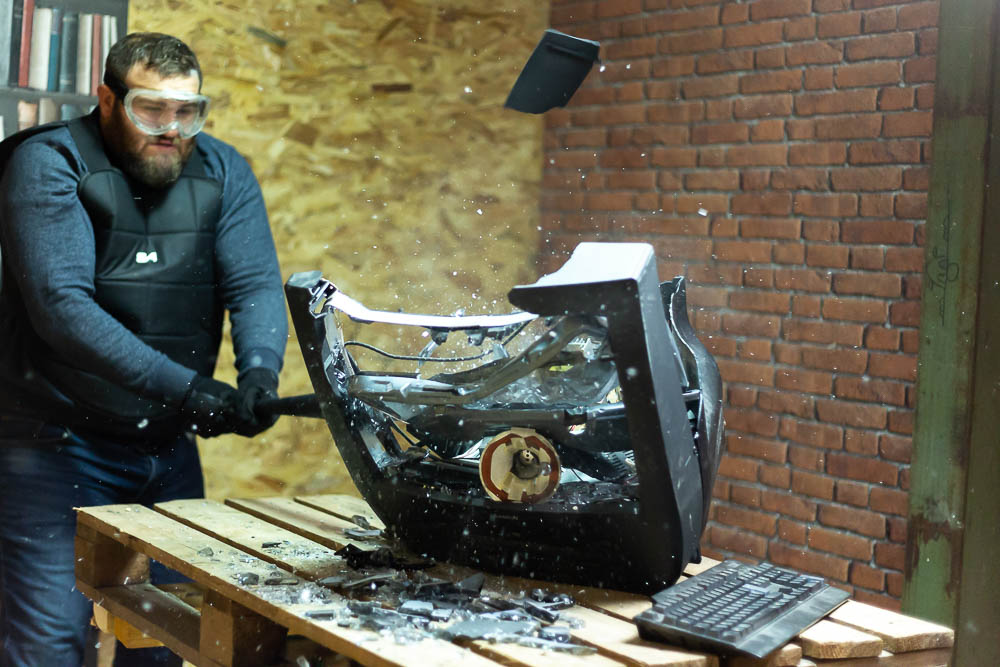 Homme explosant une télévision à coups de batte de baseball dans une rage room du Karnage Club